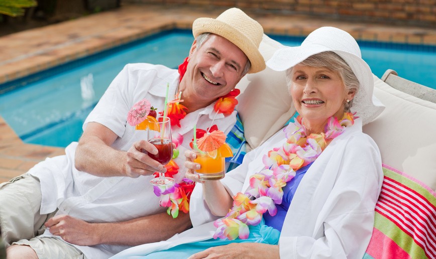 Mature couple drinking a cocktail beside the swimming pool