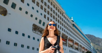 Young woman tourist photographing near the big cruise liner
