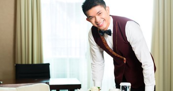 Asian Chinese room service waiter or steward serving guests food in a grand or luxury hotel room