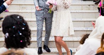 Married couple and wedding guests throwing confetti